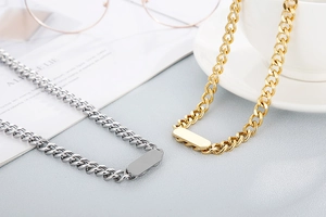 Close-up of gold and silver Cuban chain necklaces with rectangular pendants on a table