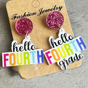 Close-up of glittery pink acrylic earrings with colorful hello FOURTH grade lettering