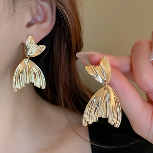 Golden fishtail earrings with pleated metal texture shown on model for elegant style