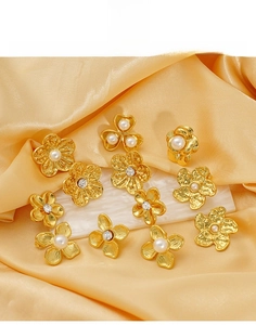 Detailed macro shot of titanium steel gold flower earrings with pearls on silk background