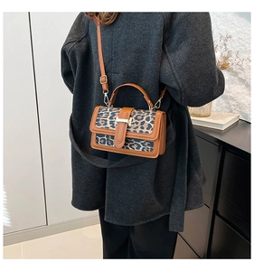 Detail of leopard print handbag with brown leather trim and metallic buckle closure