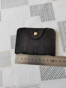 Detail view of a black PU leather card holder featuring embossed chain patterns and gold button