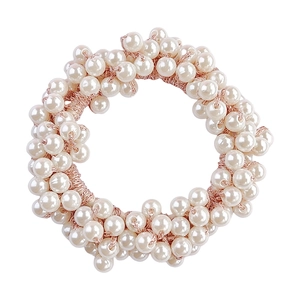 Close-up of a cream white pearl hair tie featuring lustrous beads and golden elastic cord