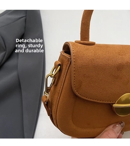 Detailed shot of brown suede crossbody bag featuring gold buckle and detachable metal hooks