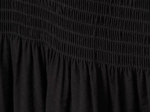 Vue macro des détails smockés noirs et de la texture plissée du tissu d'une robe
