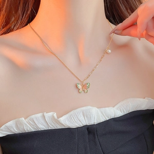 Asymmetric gold butterfly pendant necklace with pearl detail on female model's neck
