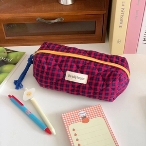 Detail of red and blue checkered quilted cosmetic bag with yellow zipper and tassel