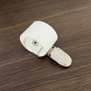 Detail eines weißen PU-Leder-Hutclips mit silberner Metallklammer auf Holzoberfläche