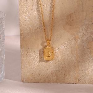 Detailed view of a gold angel relief rectangle pendant necklace with small rhinestones