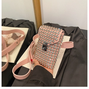 Detail showing the pink rhinestone crossbody bag with metallic buckle and strap in hand