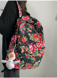 Detail view of ethnic floral backpack with red and green patterns and white plush charm