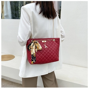 Detail of red quilted faux leather tote bag with gold chain strap and deer charm