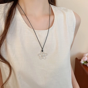 Vue détaillée du pendentif fleur évidé avec cordon noir sur le cou du mannequin