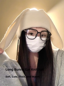 Detail of thick white knit winter hat with long decorative bunny ears and warm ear protection