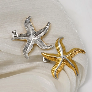 Golden and silver starfish stud earrings made of textured stainless steel on white silk