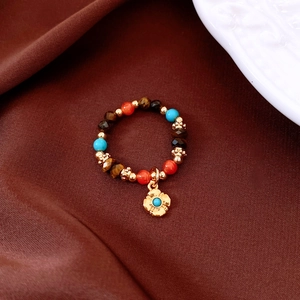 Detail of vintage beaded ring with tiger eye, turquoise beads and gold flower charm