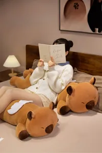 Close-up of soft plush capybara pillow with white wings in a cozy home setting