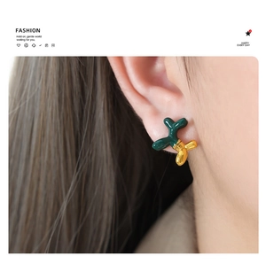 Detailed view of balloon dog earrings featuring dark green enamel and gold-plated finish