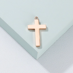 Pendentif croix minimaliste en or rose avec surface métallique lisse sur fond géométrique
