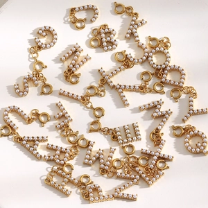 Detailed view of 18K gold plated alphabet charms with inlaid pearls and spring clasps