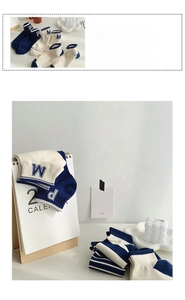 Detail of blue striped cotton ankle socks featuring decorative letter embroidery on fabric