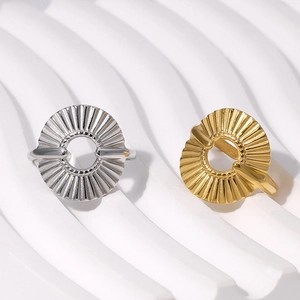 Detail of 18K gold and silver pleated stainless steel rings on a wavy texture