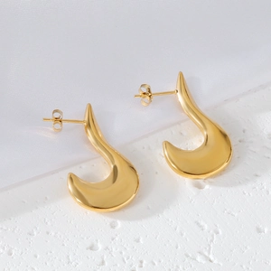 Détails des boucles d'oreilles dorées en forme de U sur marbre blanc et fond de soie