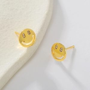 Detail shot of gold smiley face studs with cubic zirconia eyes on white ceramic