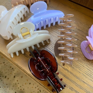 Close-up of large resin hair claws in cream, lavender, amber, and khaki on wood