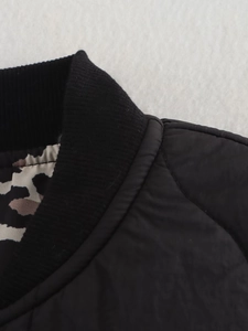 Detail of black quilted coat featuring ribbed collar and leopard print inner lining