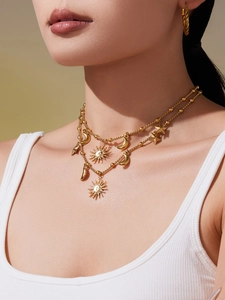 Gros plan sur l'ensemble collier et boucles d'oreilles dorés avec motifs soleil et lune