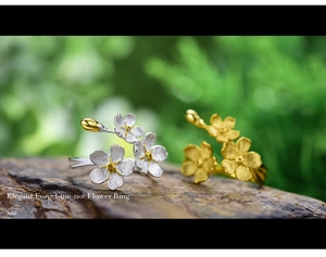 Detail of s925 silver forget-me-not rings with brushed metal petals on wood texture