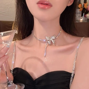 Elegant silver bow pendant necklace with crystals and tassels on model neckline