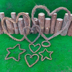 Handcrafted heart and star shaped rattan wreaths on green moss with wooden fence background