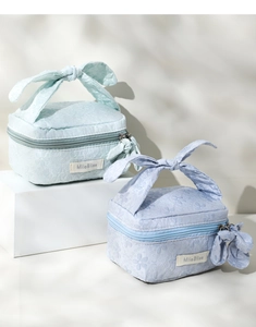 Detail of mint green and lilac jacquard makeup bags with flower embroidery and bows