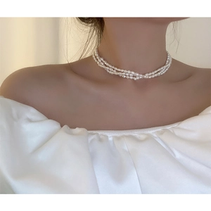 Detailed close-up of triple-layered freshwater pearl necklace on model's neck