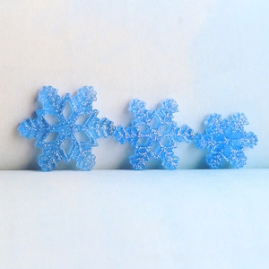 Detailed view of three blue resin snowflakes with silver glitter for DIY crafts