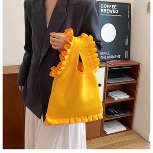 Close-up of bright yellow ruffled shoulder bag made of thick structured fabric for women