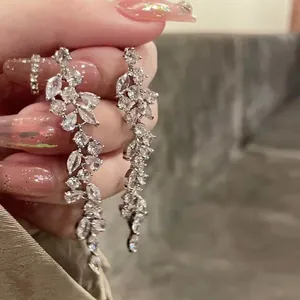 Close-up of silver leaf drop earrings with sparkling rhinestones held by hand