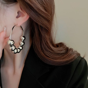 Gros plan de boucles d'oreilles créoles argentées avec perles coulissantes sur modèle