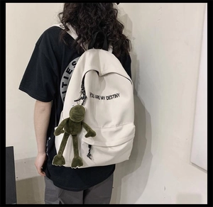 Vue arrière du sac à dos blanc cassé avec pendentif grenouille verte et texte