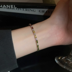 Detailed view of colorful baguette-cut zircon bracelet on wrist with elegant black background