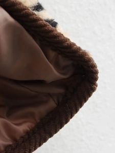Détail macro de la doublure en satin marron et du liseré en velours sur manteau léopard