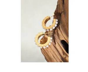 Dettaglio di orecchini a C dorati con perle bianche e finitura in metallo stile vintage