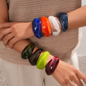 Detail of colorful chunky acrylic bangles in assorted colors on model hands