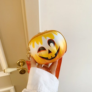 Close-up of orange round crossbody bag with pumpkin face and wide red shoulder strap