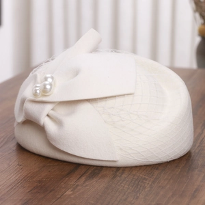 Detail of elegant wool felt pillbox hat featuring a mesh veil, large bow and pearls