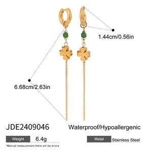 Detailed close-up of stainless steel hoop earrings with green bead and four-leaf clover tassel