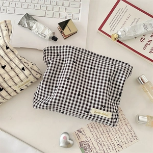 Flat lay of checkerboard and striped heart makeup bags with Korean style stationery items