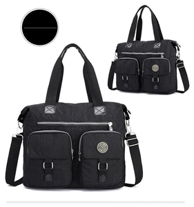 Detail of black nylon tote bag featuring front utility pockets and adjustable shoulder strap